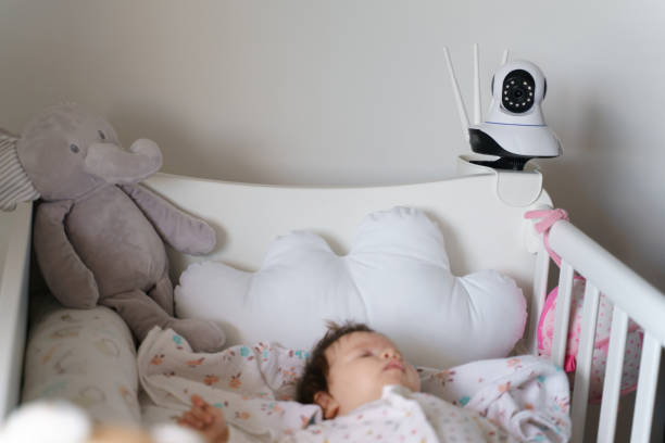 Surveillance security camera on baby bed at home in bedroom watching small child in cradle while sleeping