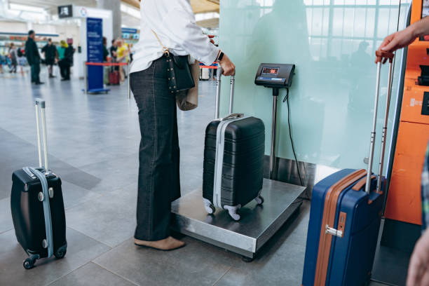 elegant woman putting suitcase on weights in airport mesuring luggage. High quality photo